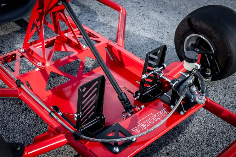 Close up of a red drift karting's pedals that are used for brake and gas. The logo The Drift Kart is visible  